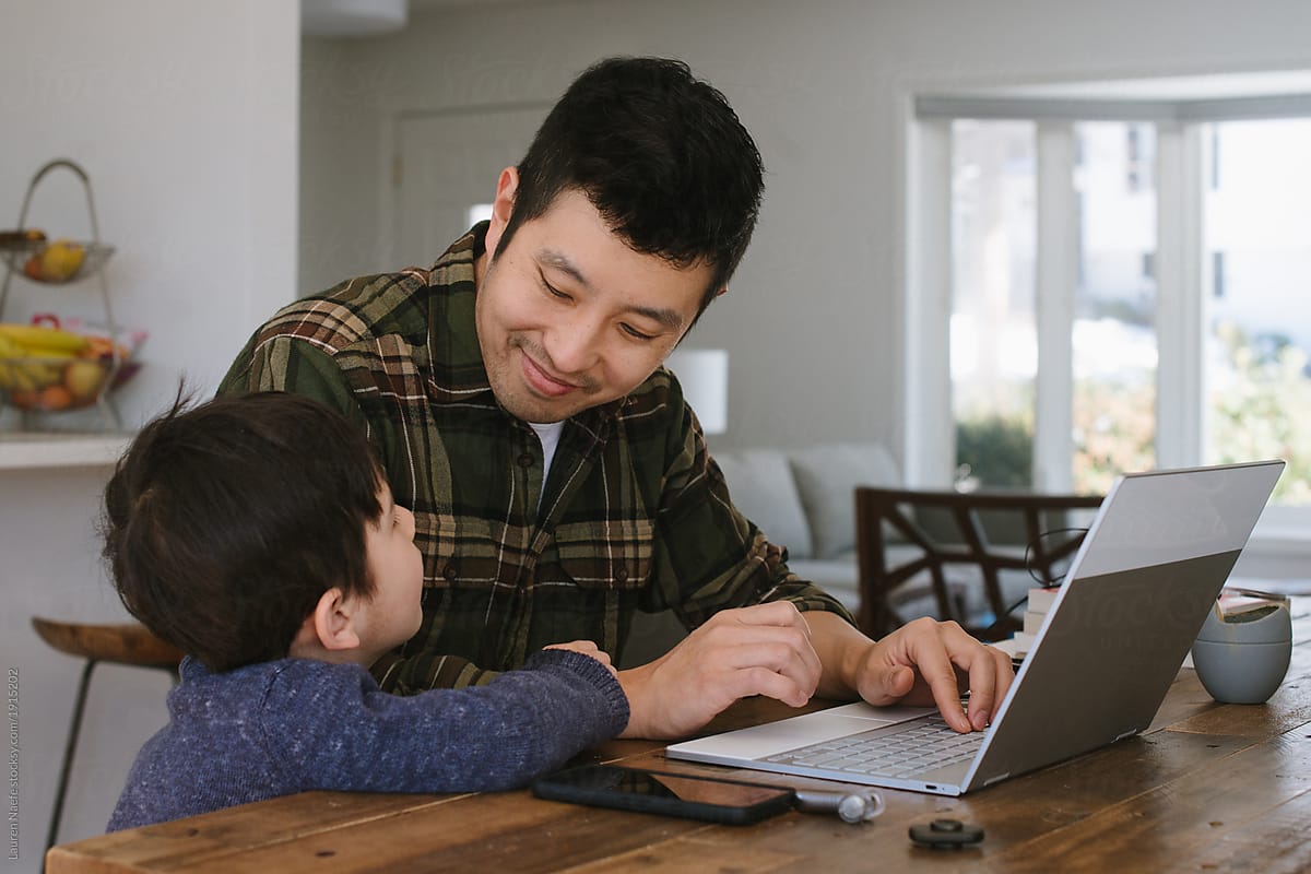 A father working on his laptop interrupted by his young son