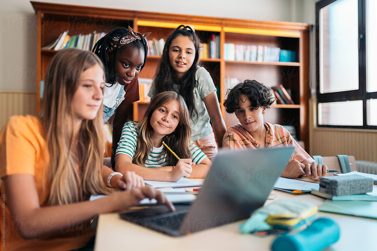 A multiethnic group of students studying together in the library while taking notes.