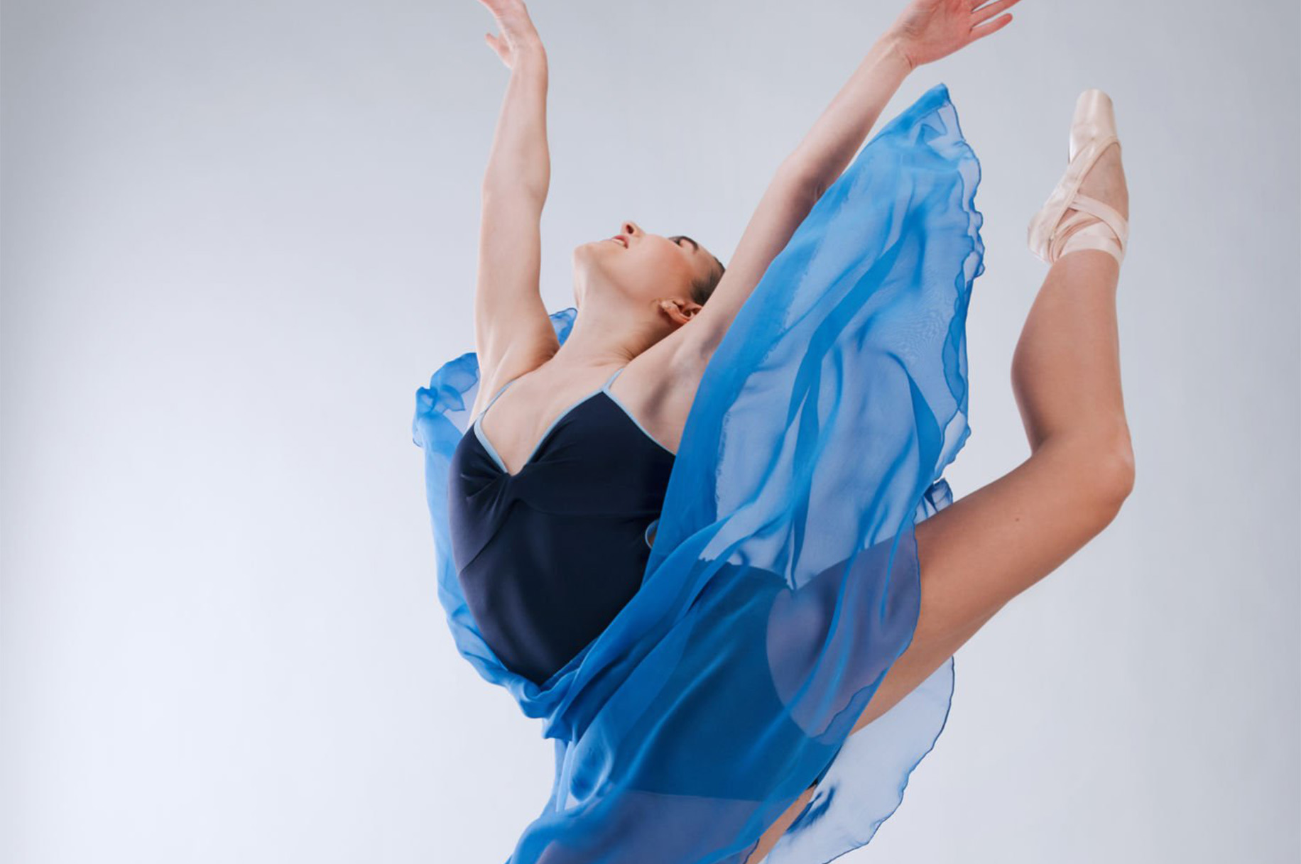 A ballerina in dark and light blue outfit in Arabesque ballet position