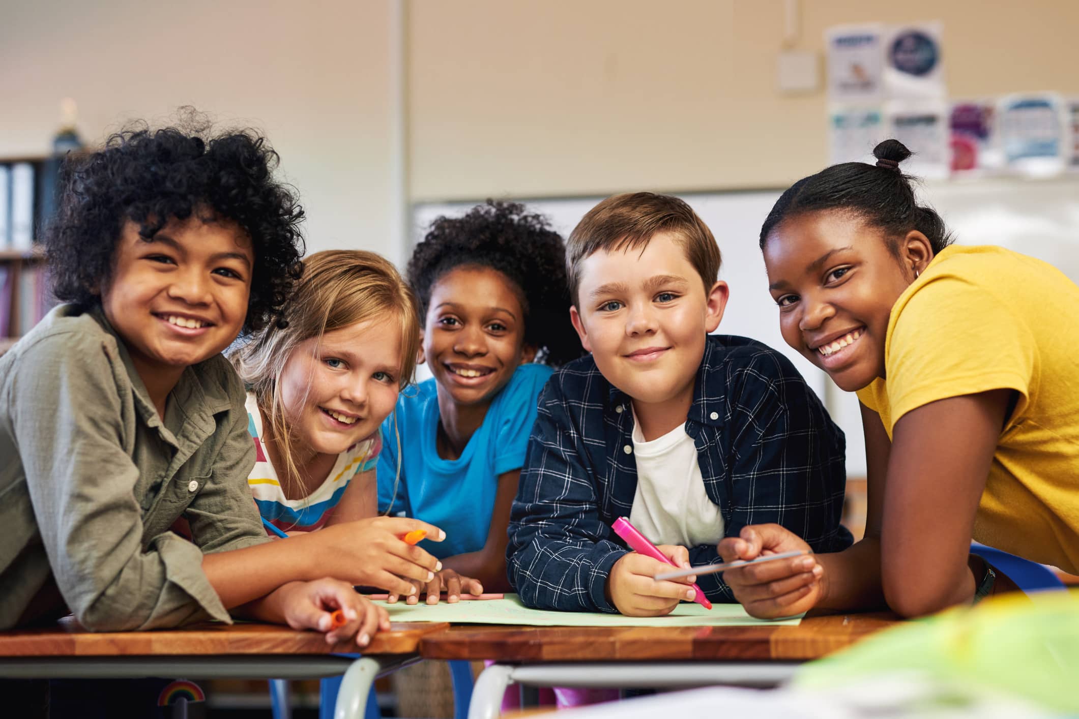 A diverse group of children huddled together in classroom working on a school project