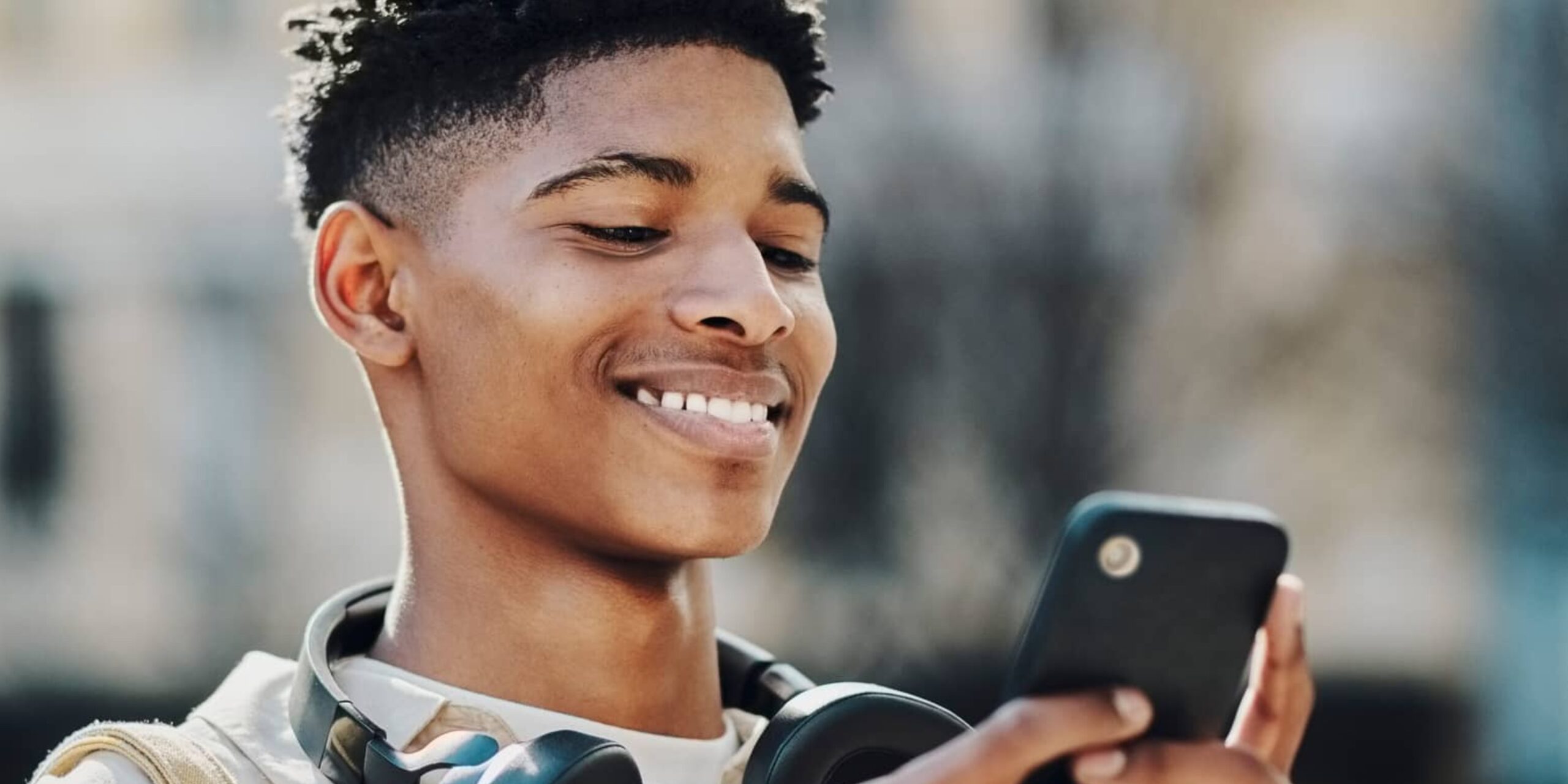 A young Black male using his smartphone to check messages or chat with friends