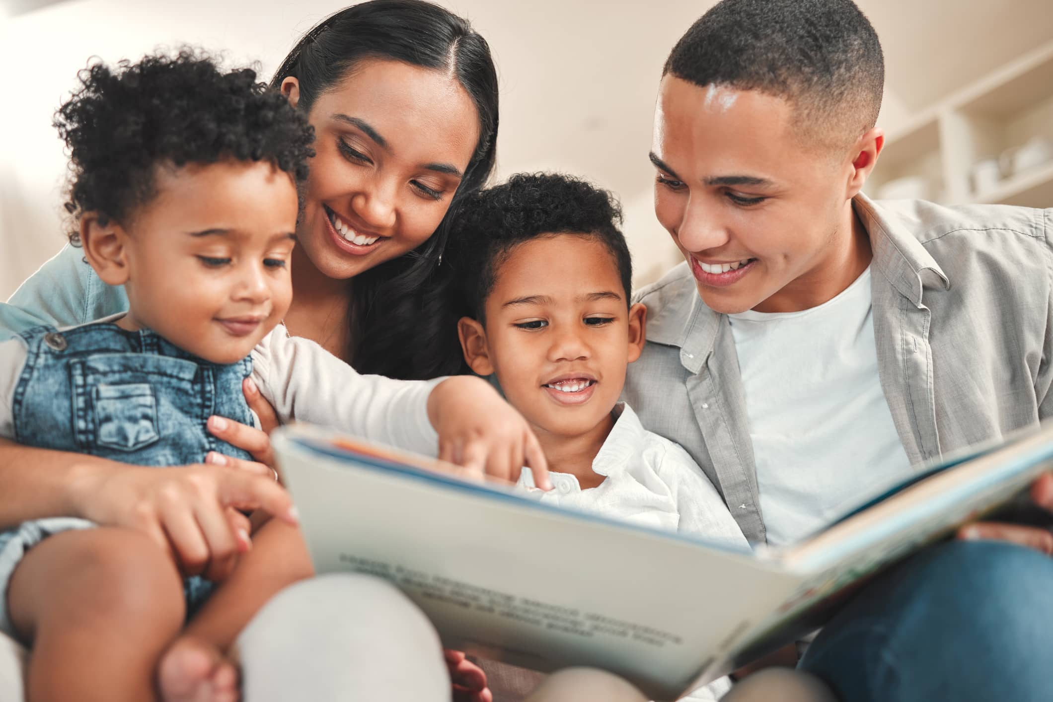 A young family reading a book together on the sofa at home