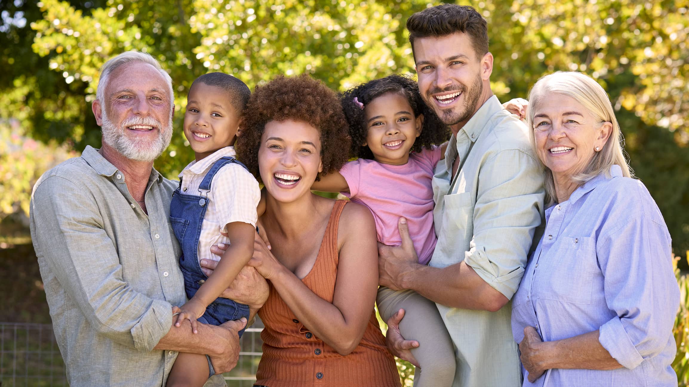 Photo of a cheerful multi-generation family standing outdoors