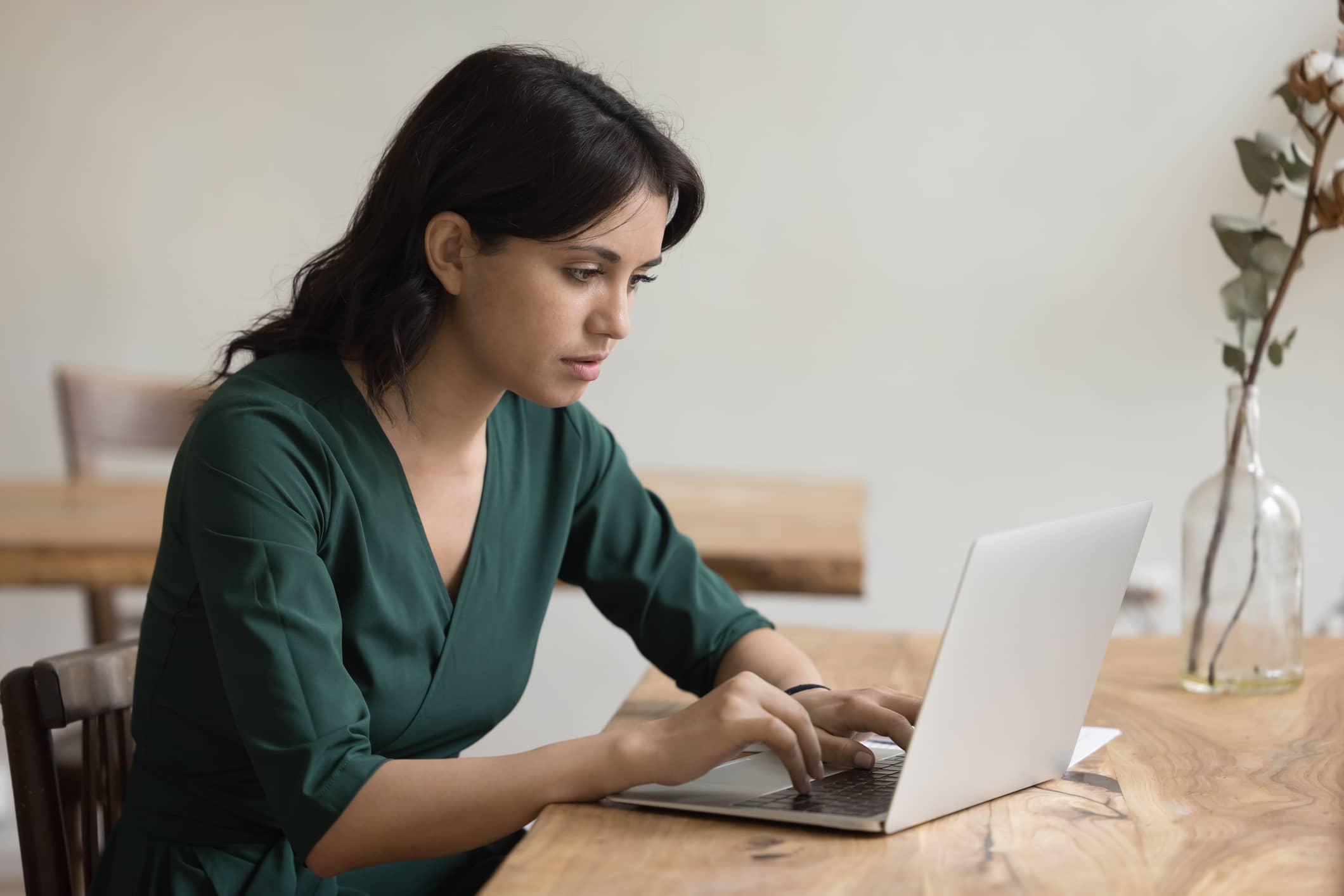 A young woman using her laptop to either study or prepare a report