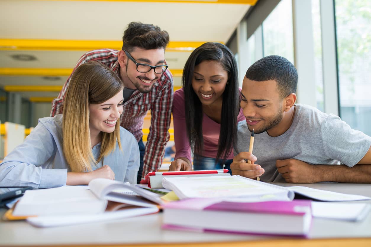 A group of four college students studying and using a digital tablet