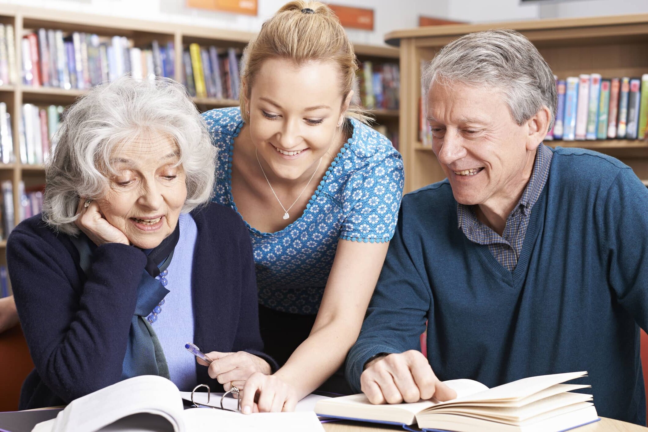 Two mature students working with teacher in library