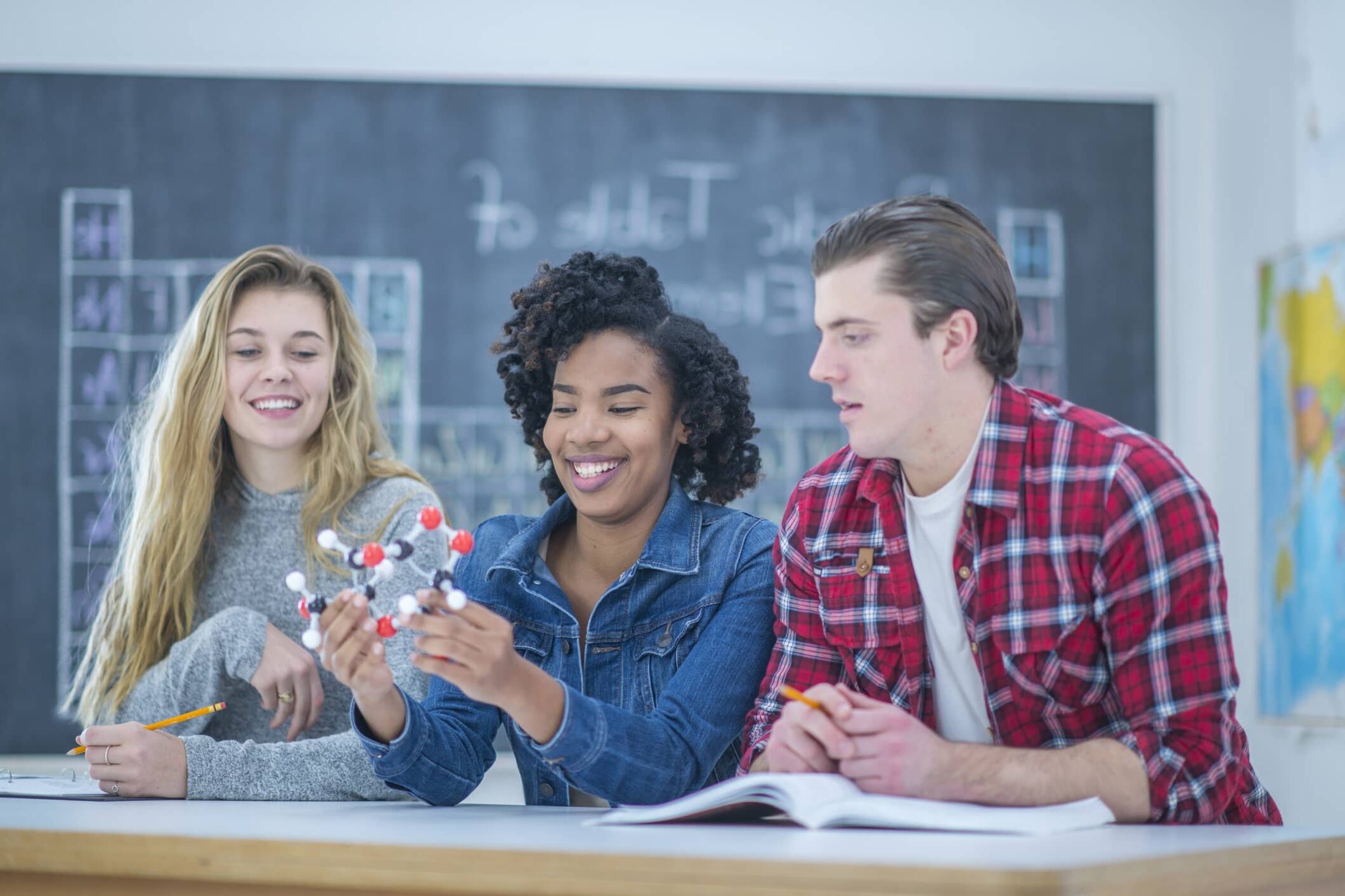 Three university students assembling a molecular model together during science class