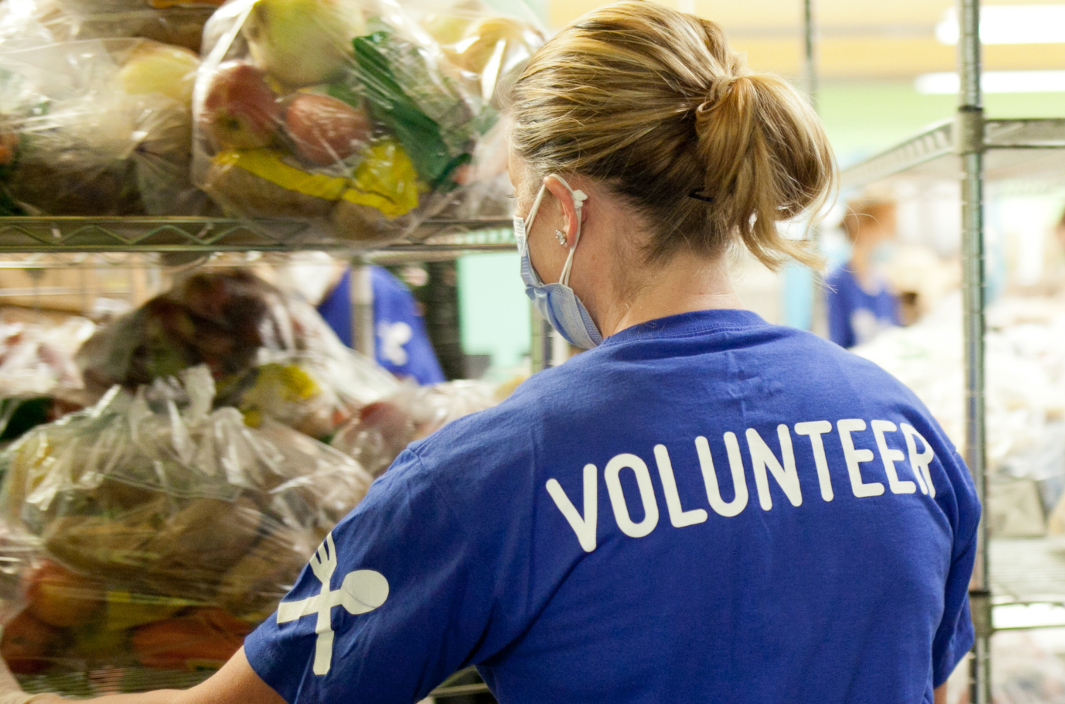 A volunteer at a food bank stocking donated food