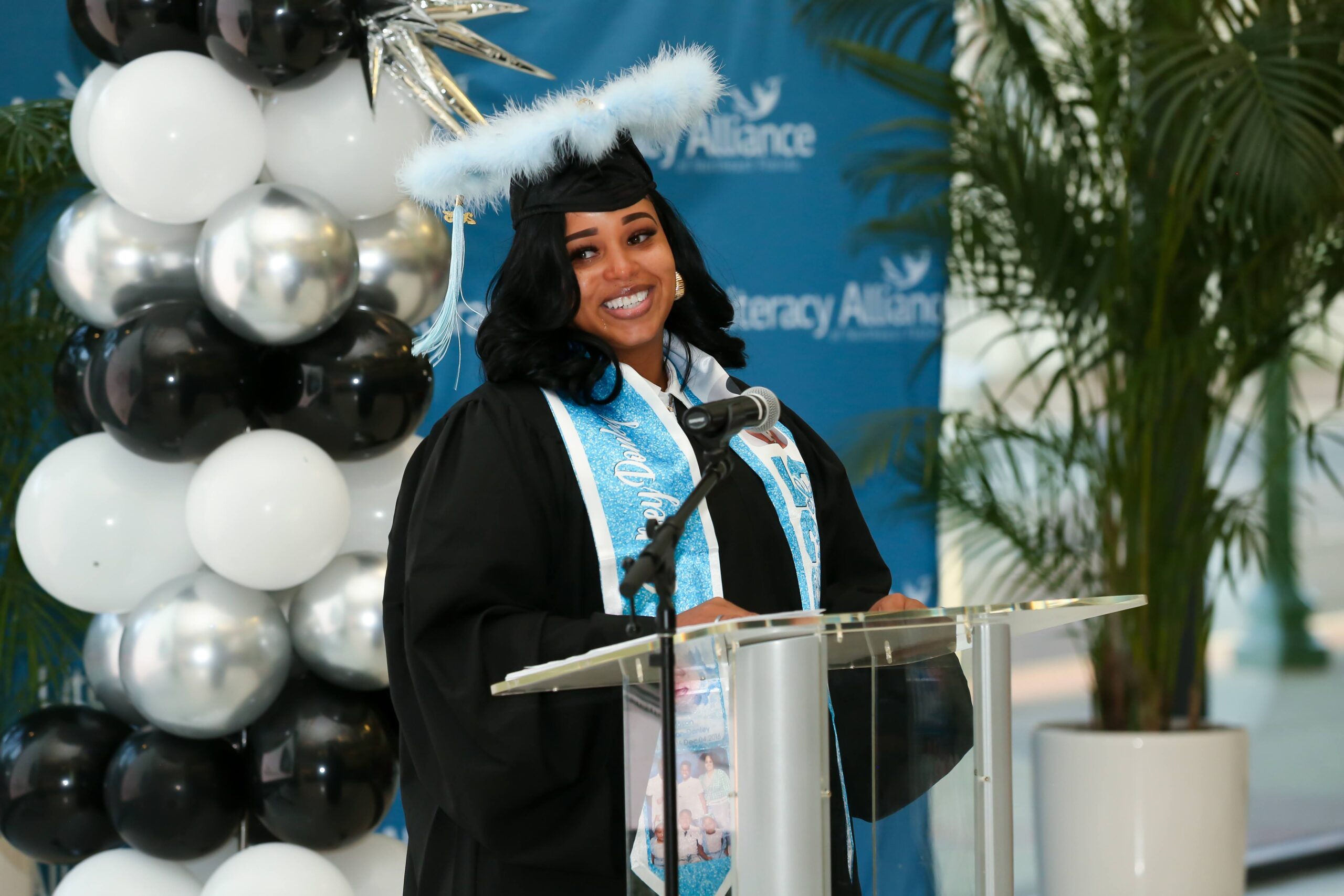 Chelsey wearing a cap and gown and standing at a podium.